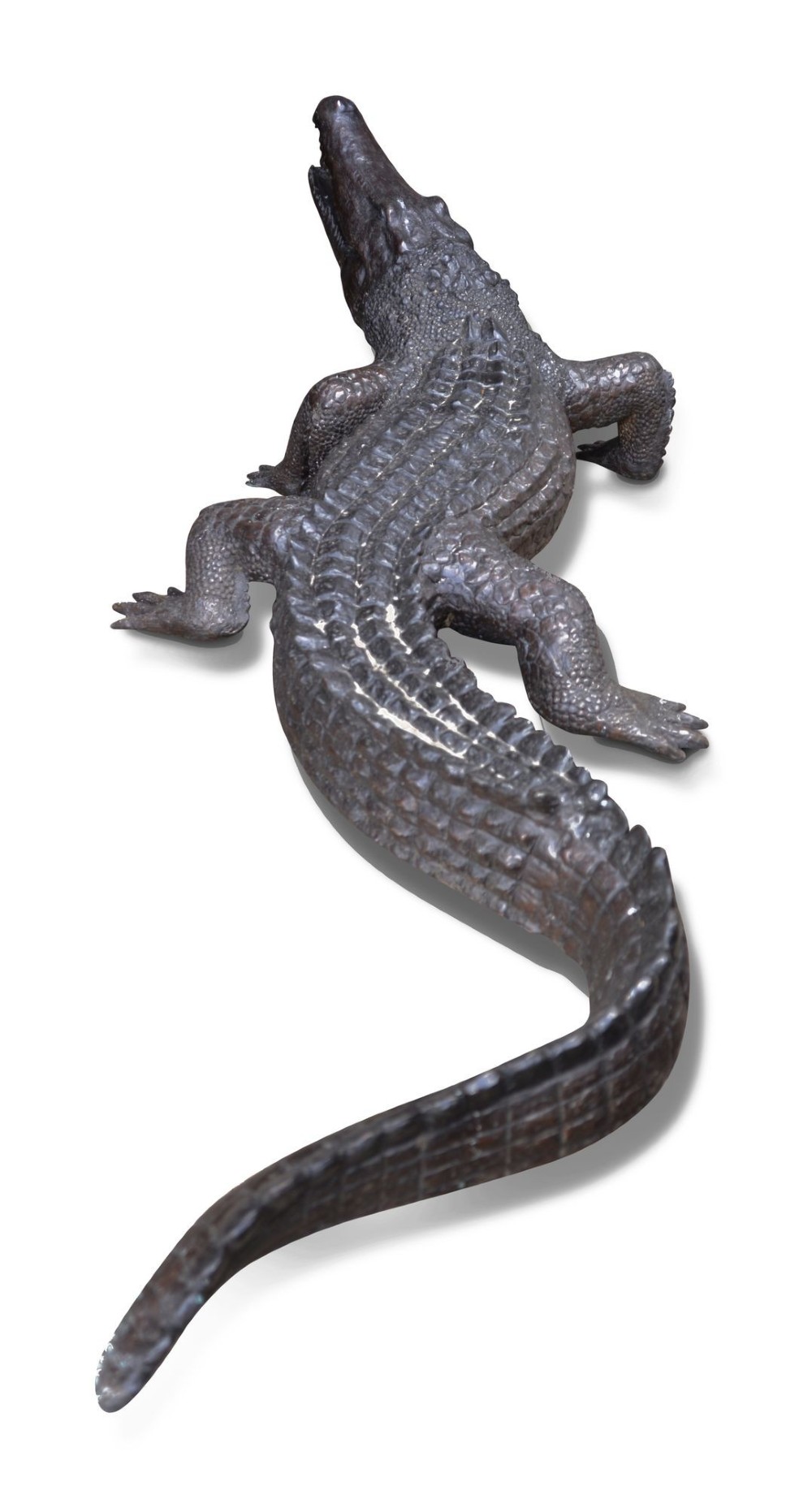 A life-size dark bronze sculpture of a crocodile depicted with open jaws, detailed scaly texture, and a curved tail. View II