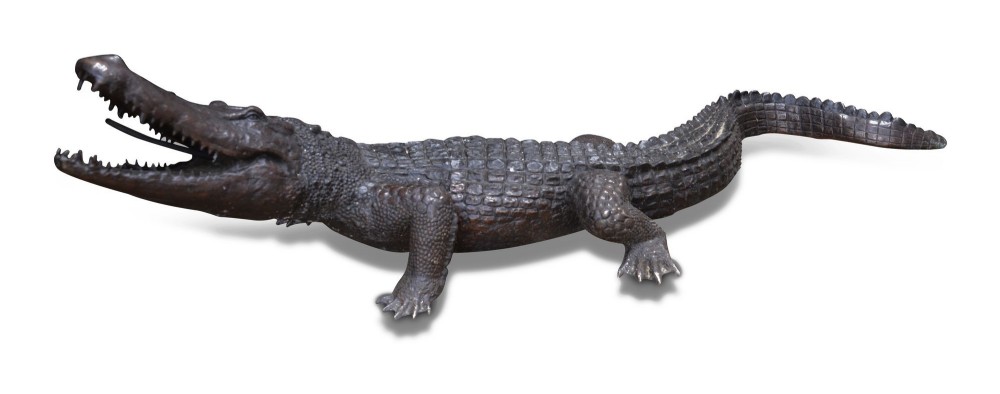 A life-size dark bronze sculpture of a crocodile depicted with open jaws, detailed scaly texture, and a curved tail. View III