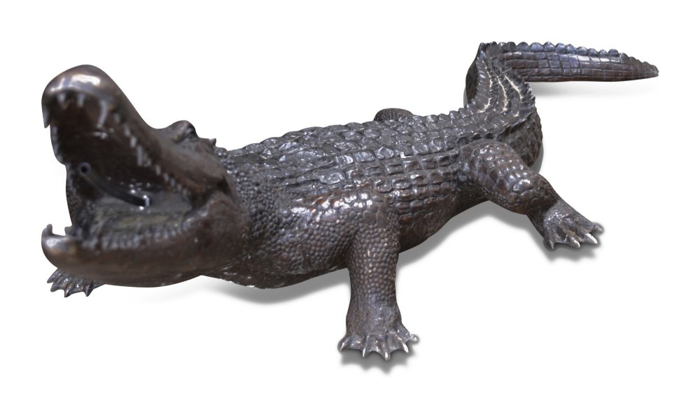 A life-size dark bronze sculpture of a crocodile depicted with open jaws, detailed scaly texture, and a curved tail. View IV