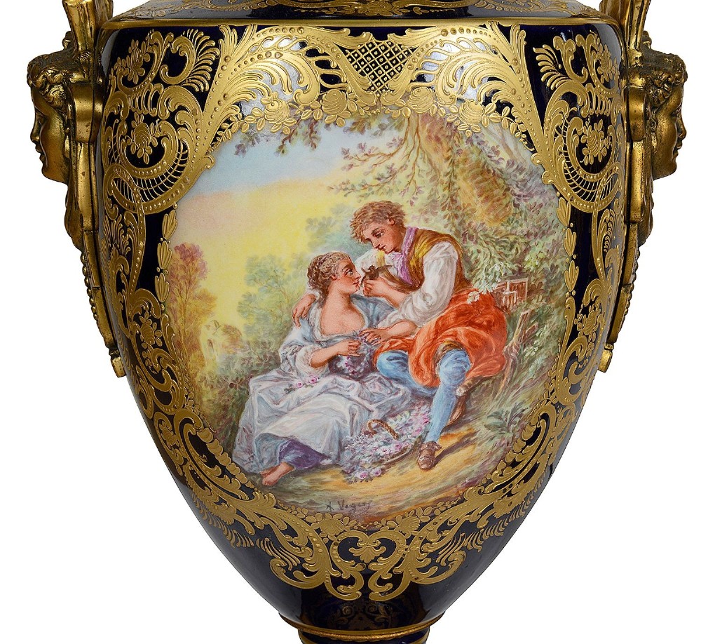 A pair of 19th-century French Sevres-style cobalt blue porcelain urn lamps featuring hand-painted romantic scenes, ornate gilt bronze mounts, and fringed fabric shades. View IV