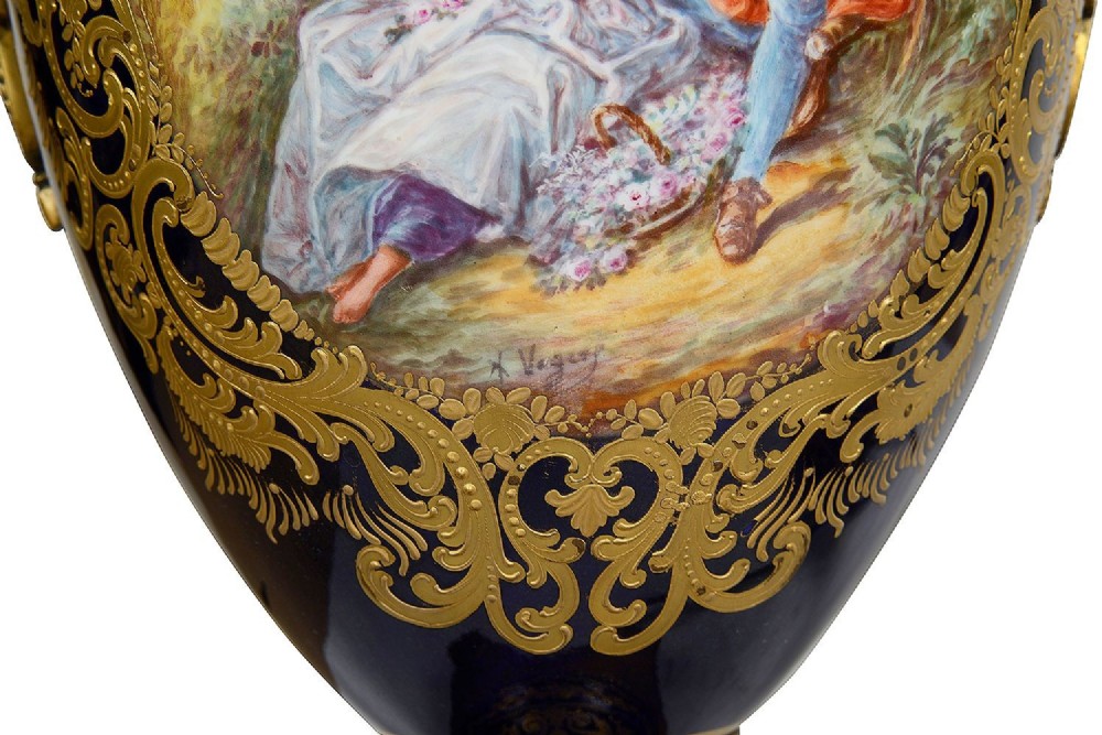 A pair of 19th-century French Sevres-style cobalt blue porcelain urn lamps featuring hand-painted romantic scenes, ornate gilt bronze mounts, and fringed fabric shades. View XII