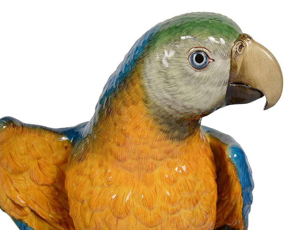 A polychrome porcelain figurine of a parrot with blue, green, and yellow feathers perched on a tree stump. View V
