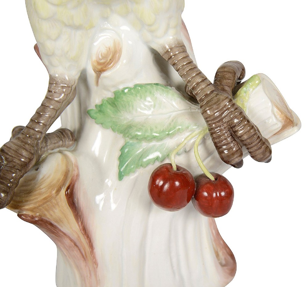 A late 19th-century Meissen porcelain parrot figurine with yellow, blue, and green plumage perched on a tree stump base with red cherries. View VII