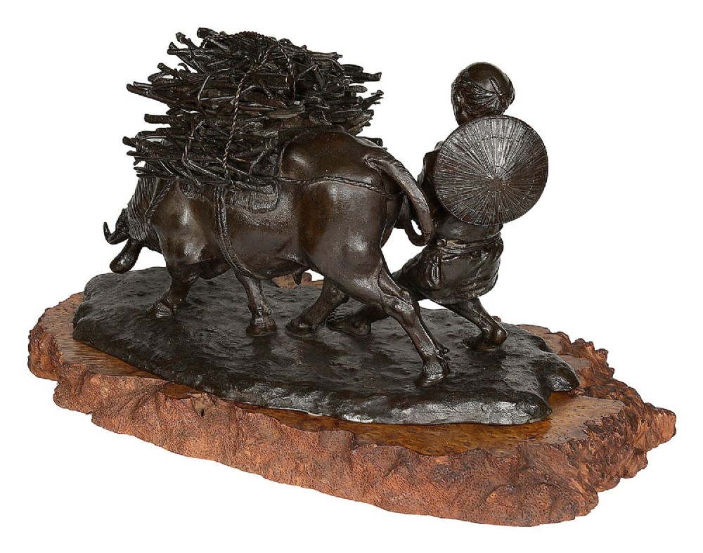 A dark patinated bronze Meiji period sculpture depicting a woodsman guiding a water buffalo laden with firewood, mounted on a rustic carved burr wood base. View VII