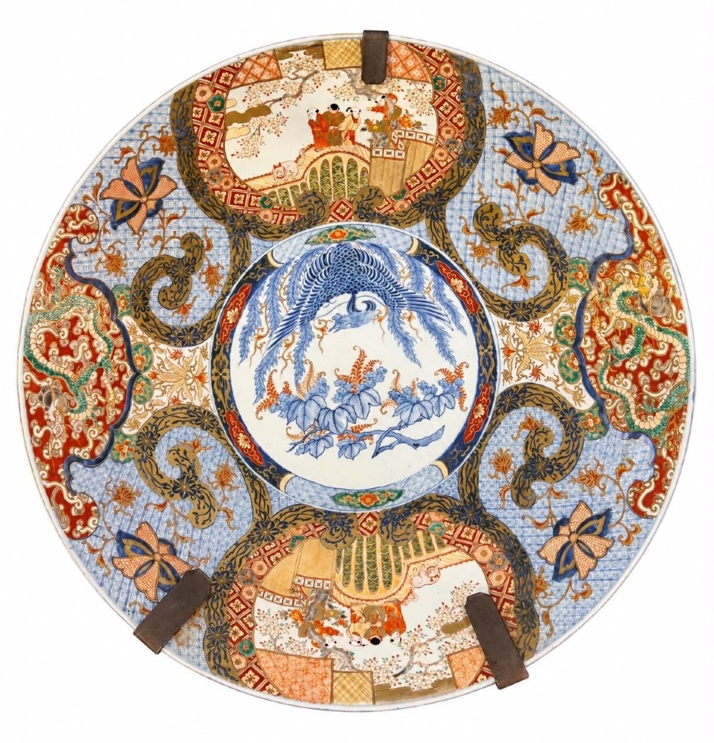 A circular 19th-century Japanese Imari porcelain charger featuring a central blue phoenix motif surrounded by intricate panels with figures, dragons, and floral patterns in blue, red, green, and gold.