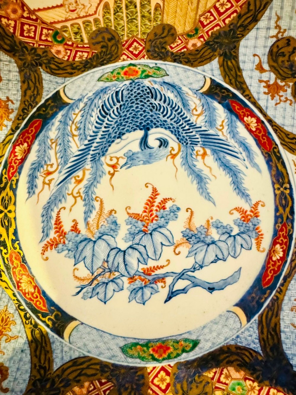 A circular 19th-century Japanese Imari porcelain charger featuring a central blue phoenix motif surrounded by intricate panels with figures, dragons, and floral patterns in blue, red, green, and gold. View III
