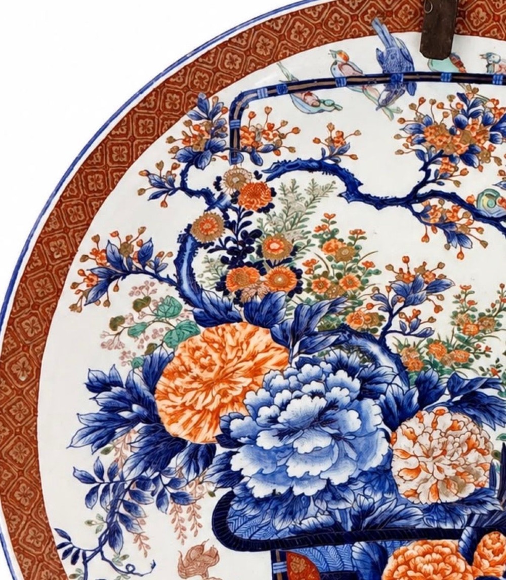 A large circular Japanese Imari porcelain charger decorated with a central blue and orange flower basket and geometric border. View II
