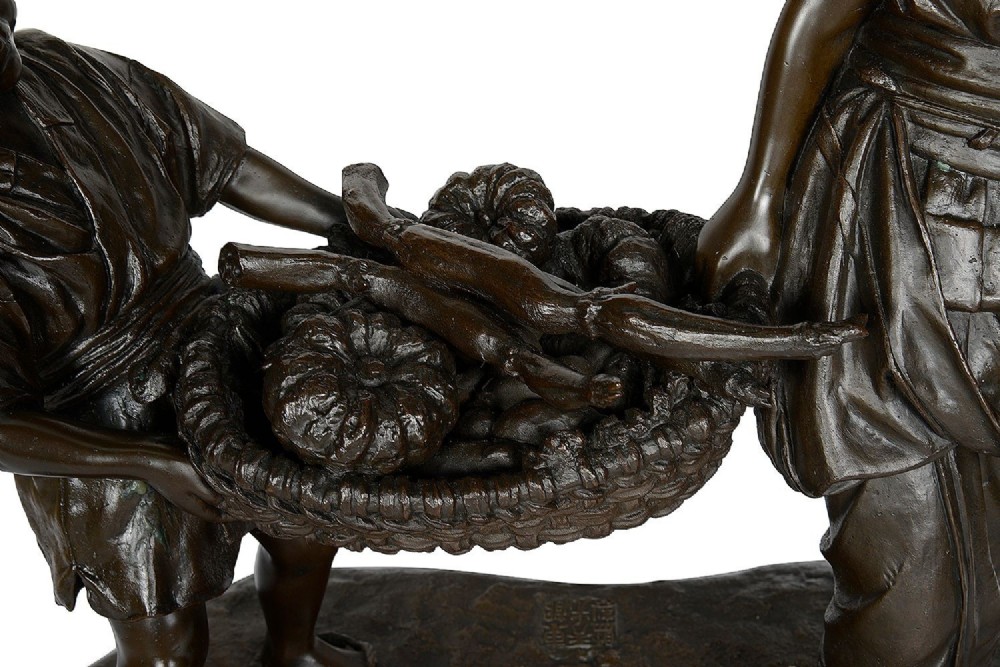 A dark brown patinated bronze sculpture depicting a Japanese woman and child carrying a woven basket filled with produce across a textured base. View II
