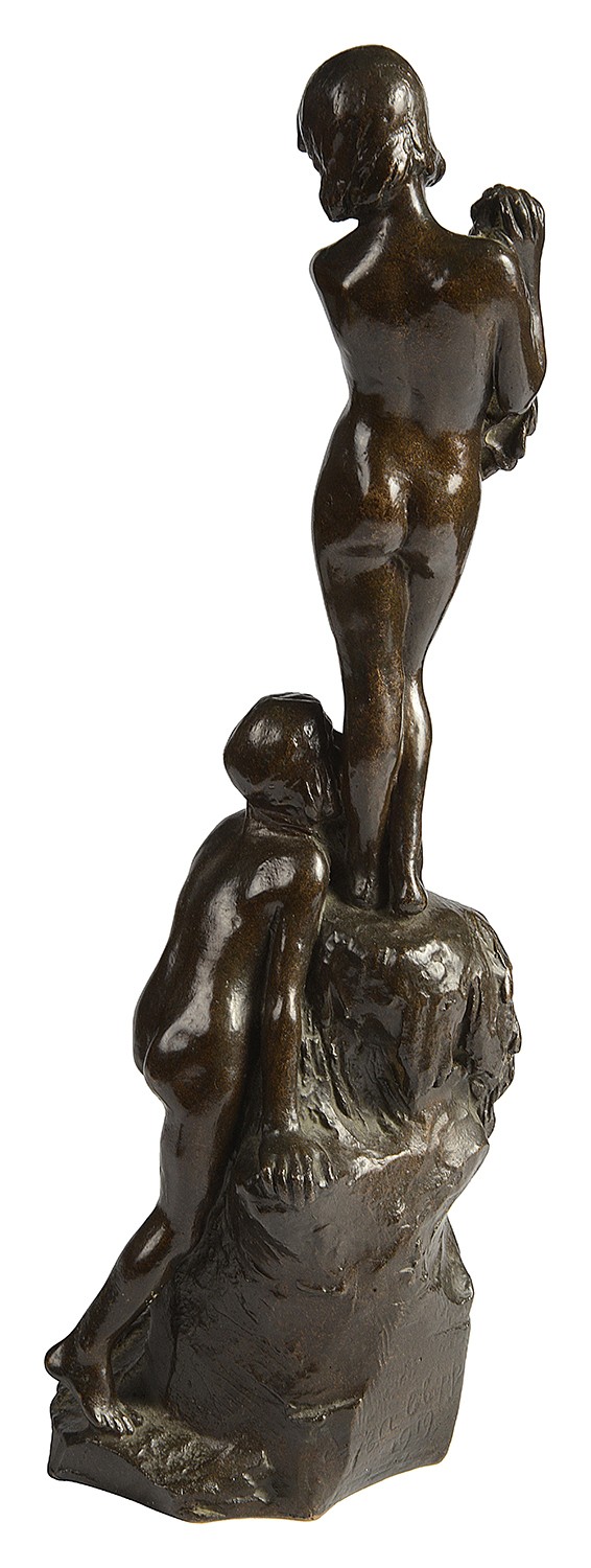 A dark brown patinated bronze sculpture depicting two young children near a rock formation, with one standing above holding a towel and the other crouching at the base. View V