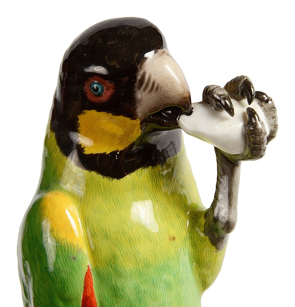 A 19th-century Meissen porcelain figurine featuring a colourful green, yellow, and black parrot perched atop a white tree trunk decorated with red cherries. View V