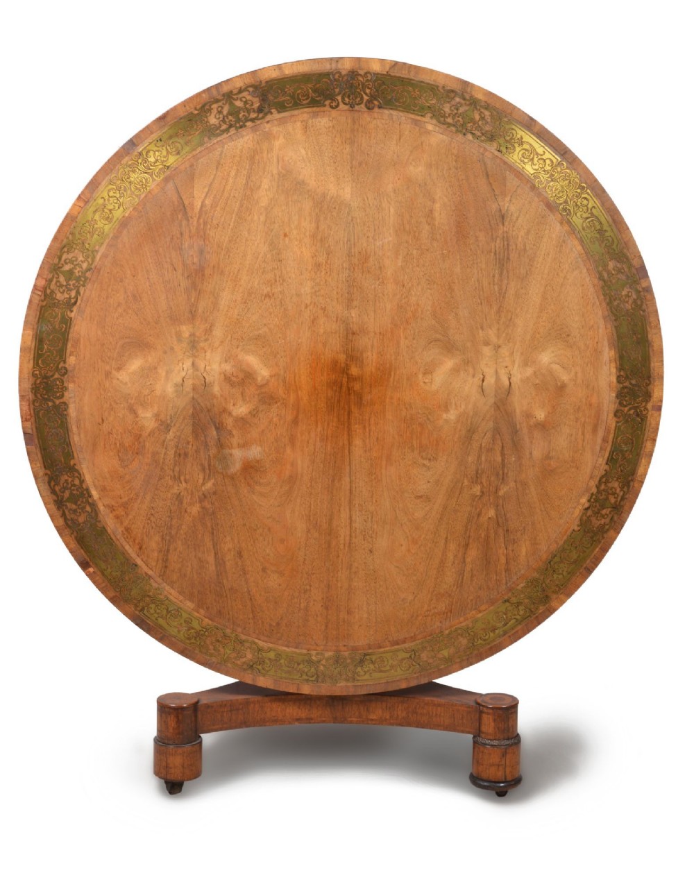 A circular Regency period timber centre table featuring a floral brass inlaid border, a central tapered pedestal stem, and a tripartite base resting on cylindrical feet with castors. View III