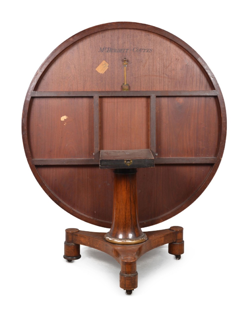 A circular Regency period timber centre table featuring a floral brass inlaid border, a central tapered pedestal stem, and a tripartite base resting on cylindrical feet with castors. View V