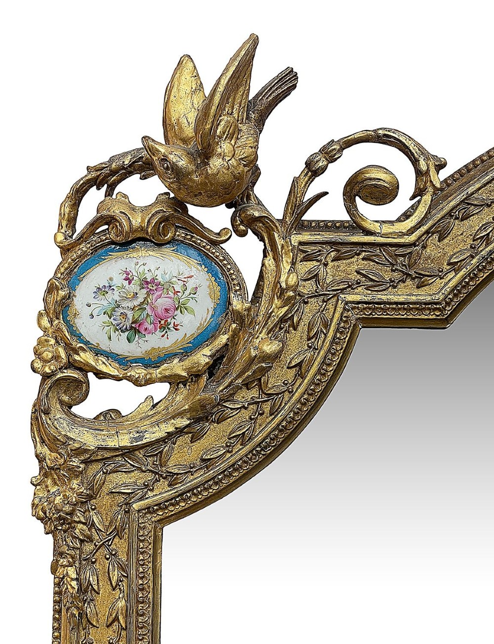 A large gilt-bronze wall mirror featuring an arched crest with sculpted putti, foliage mouldings, and oval Sevres porcelain plaques set along the frame. View IV