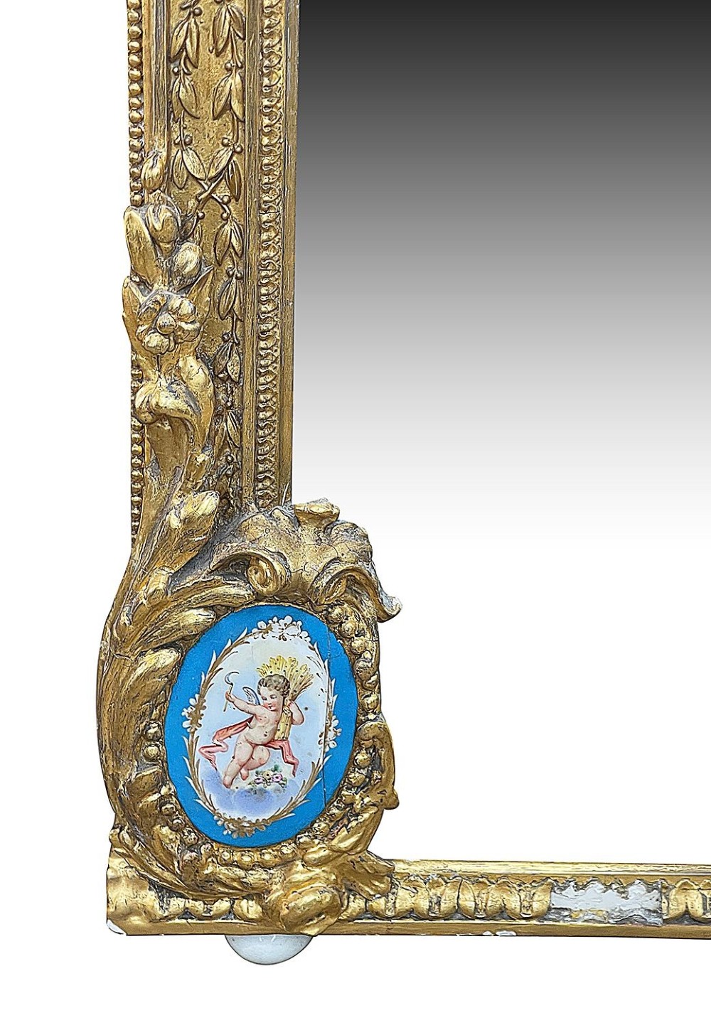 A large gilt-bronze wall mirror featuring an arched crest with sculpted putti, foliage mouldings, and oval Sevres porcelain plaques set along the frame. View IX