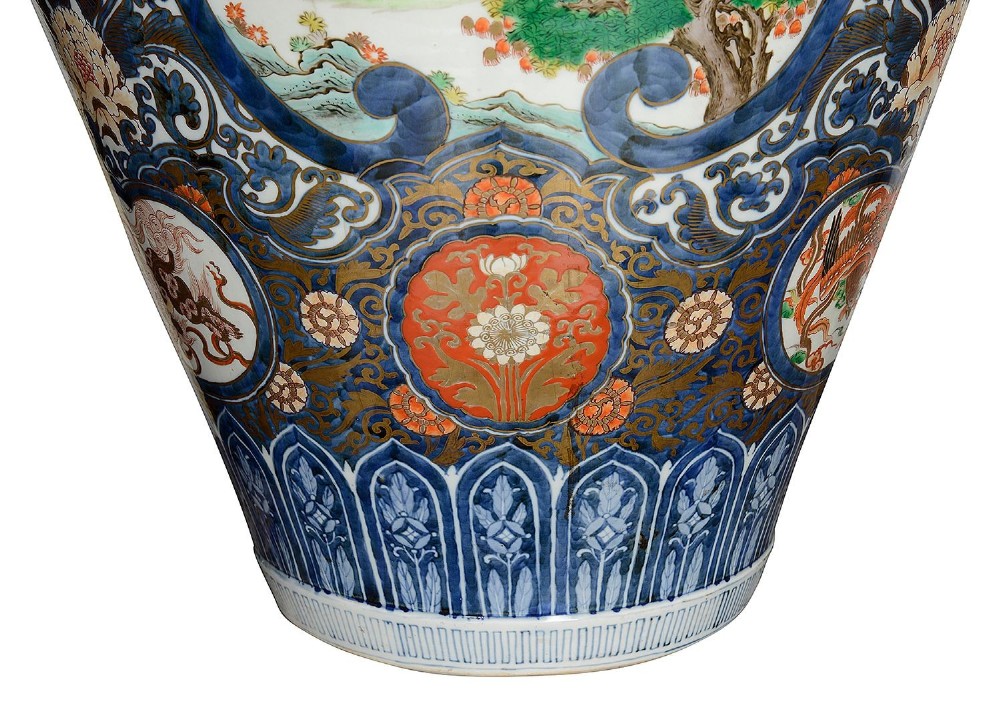 A pair of large 19th-century Japanese Imari porcelain lidded vases featuring painted reserves depicting figures in garden settings, surrounded by cobalt blue, orange, green, and gold patterns. View III