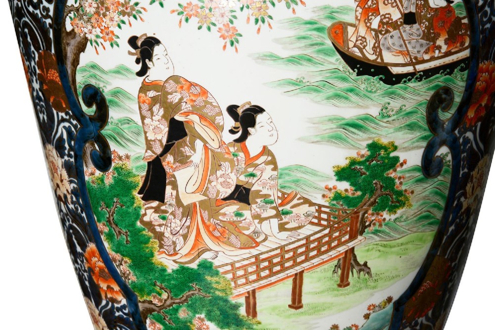 A pair of large 19th-century Japanese Imari porcelain lidded vases featuring painted reserves depicting figures in garden settings, surrounded by cobalt blue, orange, green, and gold patterns. View VIII
