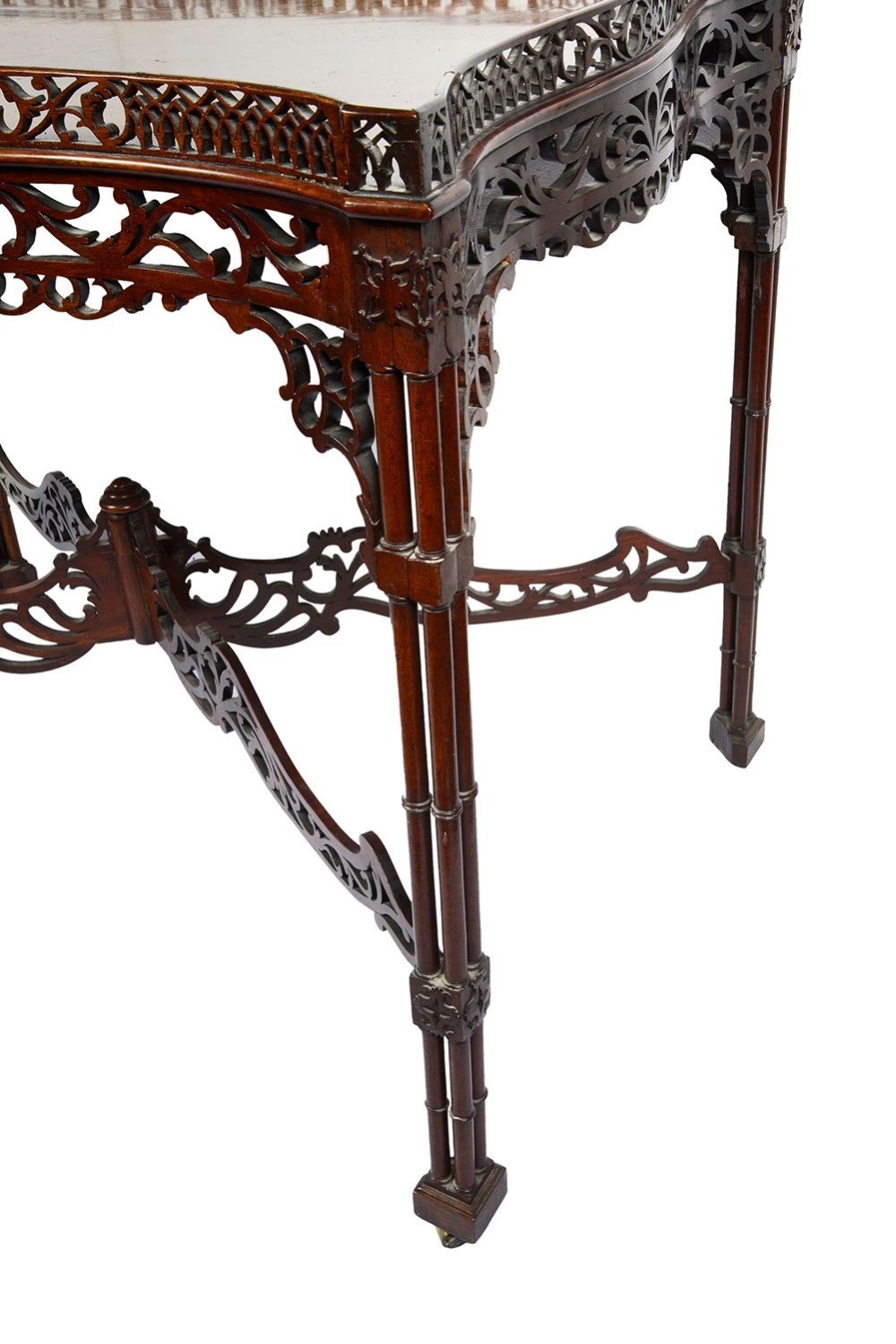 A dark mahogany Chippendale style silver table featuring a serpentine top, pierced fretwork gallery, pierced apron, and cluster legs with an X-stretcher. View III