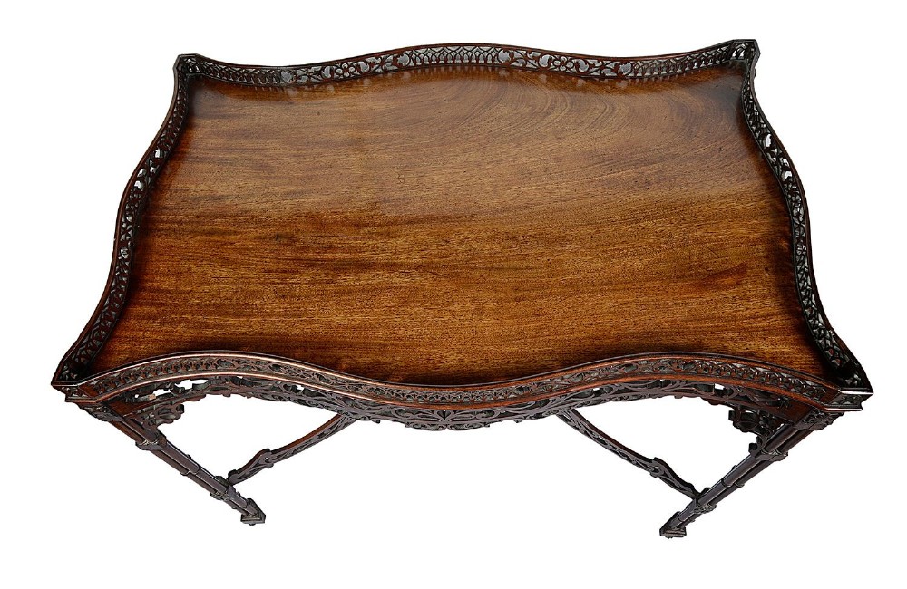A dark mahogany Chippendale style silver table featuring a serpentine top, pierced fretwork gallery, pierced apron, and cluster legs with an X-stretcher. View VI
