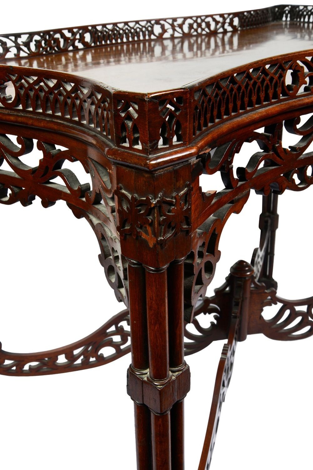 A dark mahogany Chippendale style silver table featuring a serpentine top, pierced fretwork gallery, pierced apron, and cluster legs with an X-stretcher. View IX