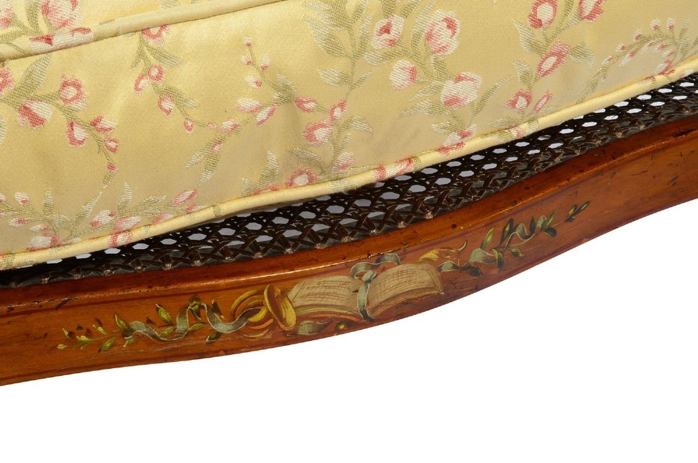 A pair of late Victorian Sheraton Revival satinwood bergere armchairs featuring hand-painted floral motifs, portrait medallions, caned backs, and yellow fabric seats. View VIII