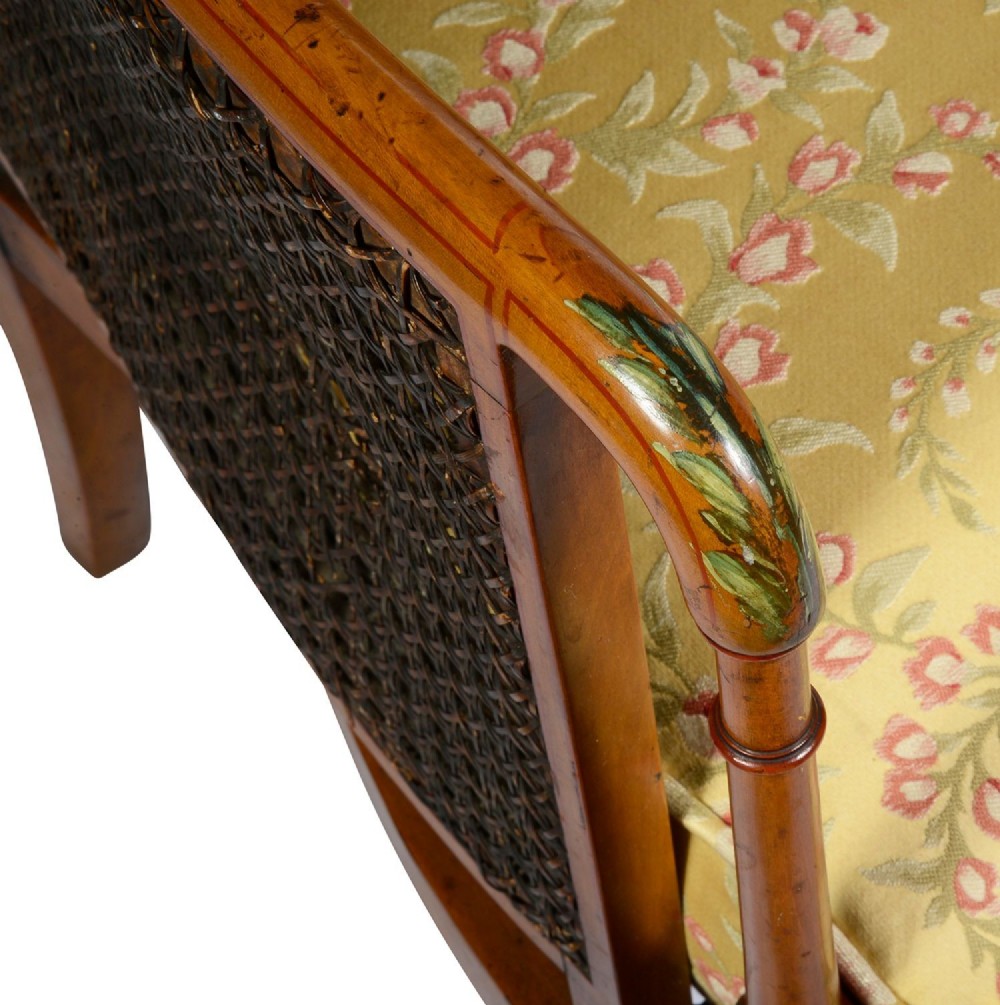 A pair of late Victorian Sheraton Revival satinwood bergere armchairs featuring hand-painted floral motifs, portrait medallions, caned backs, and yellow fabric seats. View IX