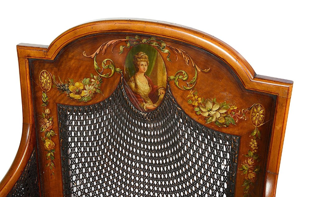 A pair of late Victorian Sheraton Revival satinwood bergere armchairs featuring hand-painted floral motifs, portrait medallions, caned backs, and yellow fabric seats. View XII