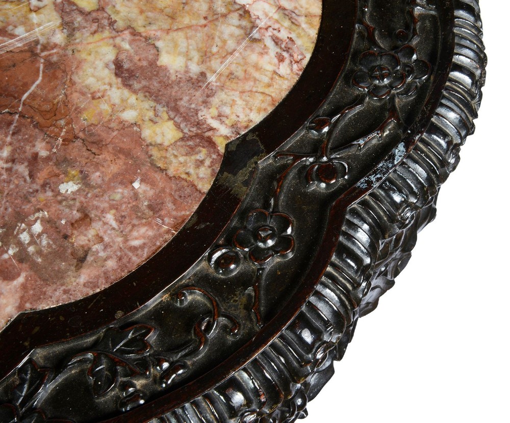 A nineteenth-century Chinese carved dark hardwood side table featuring a circular pink marble inset top, pierced openwork frieze, reticulated central pedestal, and tripod clawed feet. View V