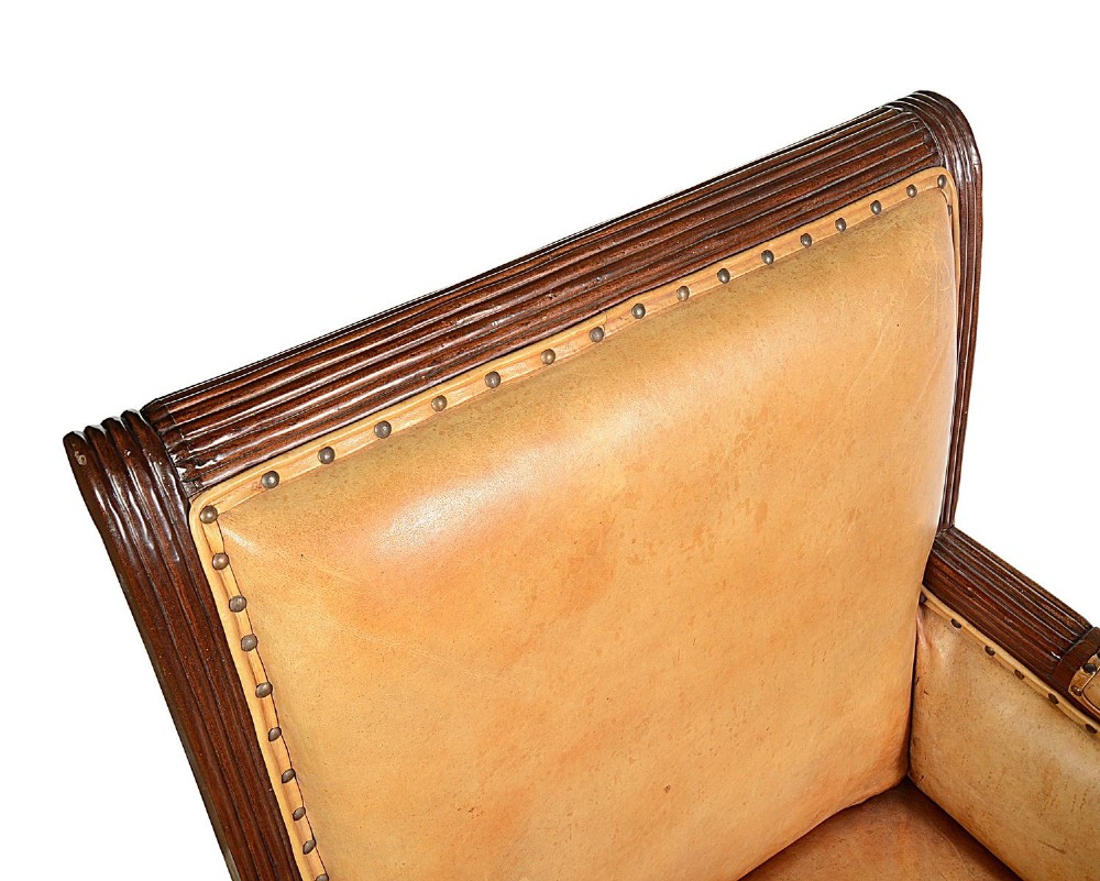 A pair of Regency style dark mahogany library armchairs upholstered in tan leather with brass stud trimming and reeded carved legs. View VI
