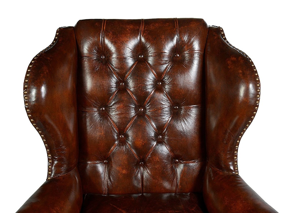 A pair of Georgian style chestnut brown leather wingback armchairs featuring deep button tufting, brass stud trimming, and carved cabriole legs. View V