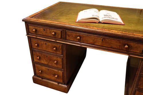 fig 2. A Victorian oak and burr walnut pedestal desk featuring nine drawers with turned wooden knob handles and a central kneehole.