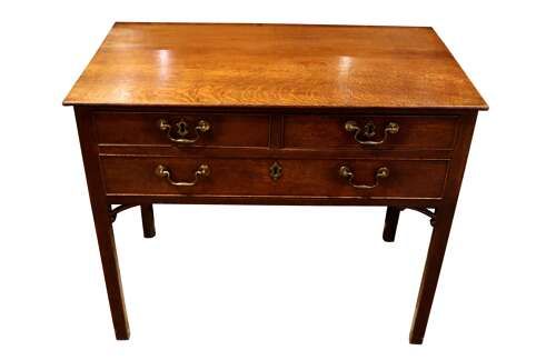 fig 2. A George III dark oak lowboy featuring a rectangular top over three drawers with brass swan-neck handles, supported on straight square legs.