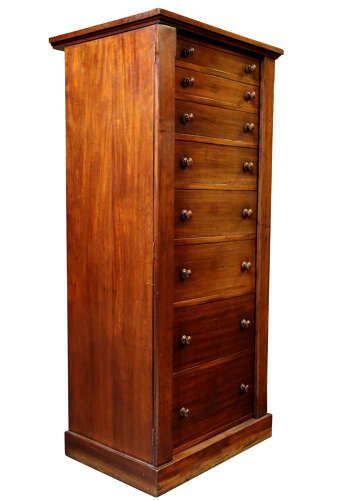 fig 1. A tall mid-19th century mahogany Wellington chest featuring eight graduated drawers with turned wooden knobs and a side-locking hinged pilaster.