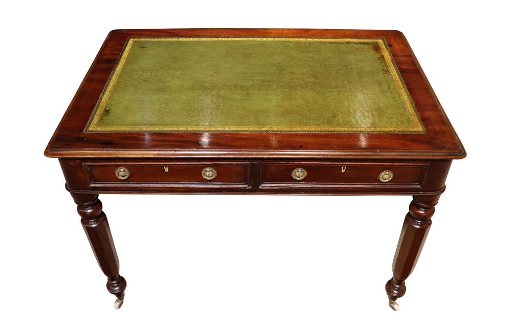 A William IV mahogany writing table featuring a green leather inset top with gold tooling, two frieze drawers, turned legs, and brass castors.