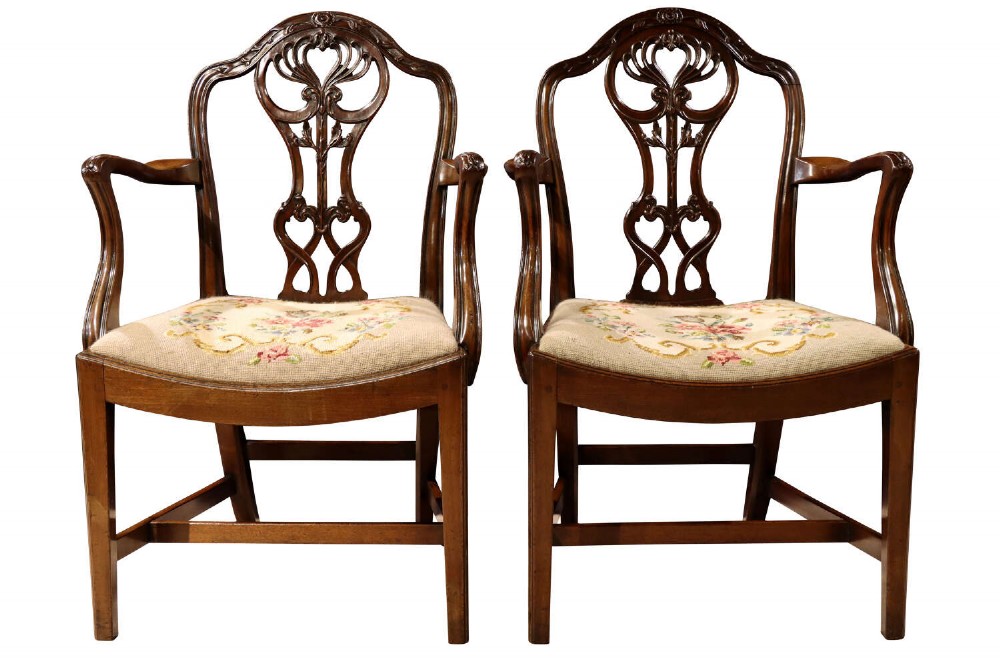 A pair of Edwardian mahogany Chippendale Revival open armchairs featuring carved pierced splats and embroidered floral tapestry drop-in seats.
