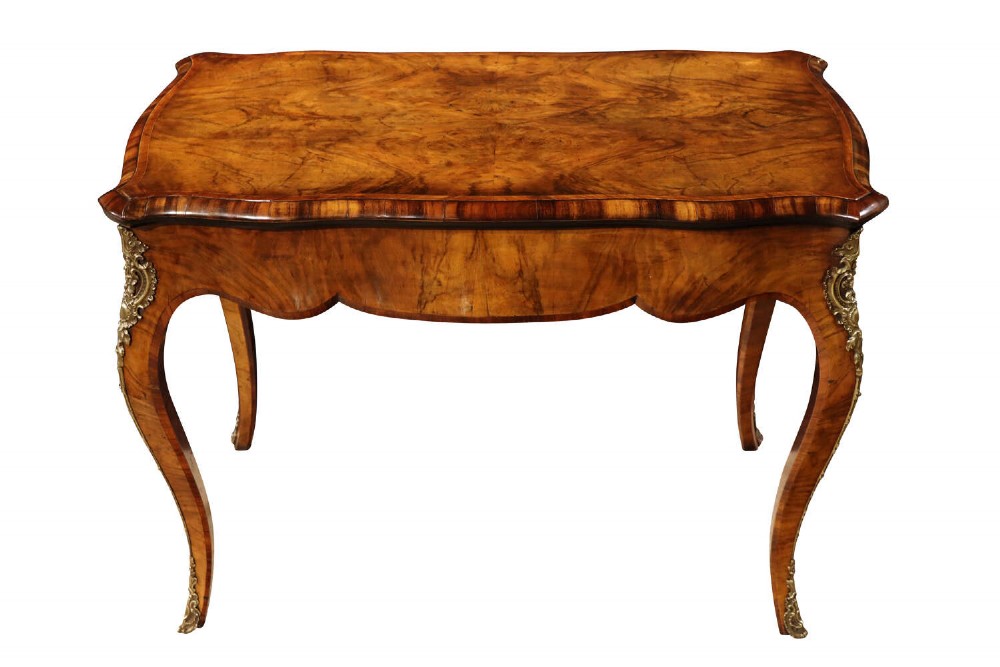 A mid-19th century French Louis XV style card table crafted from burr walnut with a serpentine top, cabriole legs, and gilt-bronze mounts.