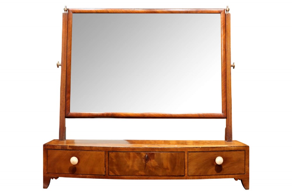 A Regency mahogany dressing table mirror featuring a rectangular swivelling glass frame supported by reeded side uprights above a three-drawer base.