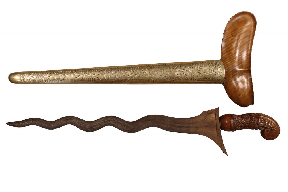 A 19th-century Malay keris featuring a wavy forged steel blade alongside a carved wooden hilt and an ornate brass-encased sheath.