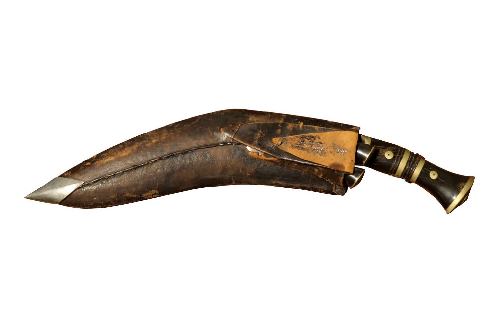 An early 20th-century Nepalese kukri dagger housed in a dark leather scabbard featuring a carved horn handle and two small companion knives.