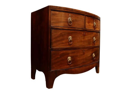 A George III bow-fronted mahogany chest of drawers featuring two short over two long drawers with brass lion mask ring handles and splayed feet. View IV
