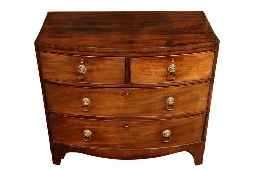 A George III bow-fronted mahogany chest of drawers featuring two short over two long drawers with brass lion mask ring handles and splayed feet. View V