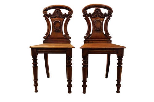 A pair of mid-Victorian mahogany hall chairs with carved shield backrests, solid seats, and turned front legs. View II