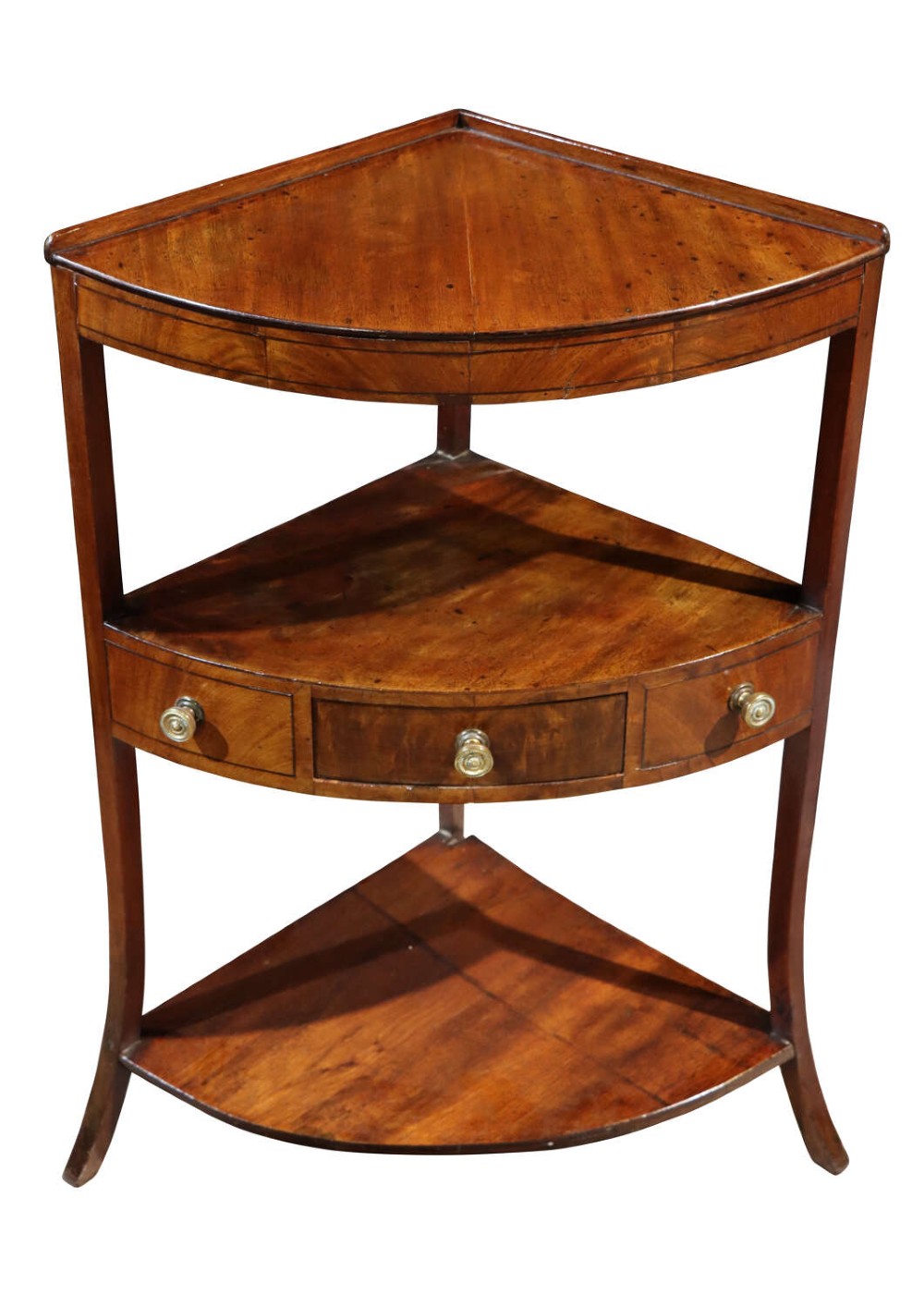 An early 19th-century mahogany corner washstand featuring three triangular tiers, a central drawer with brass knobs, and splayed legs.