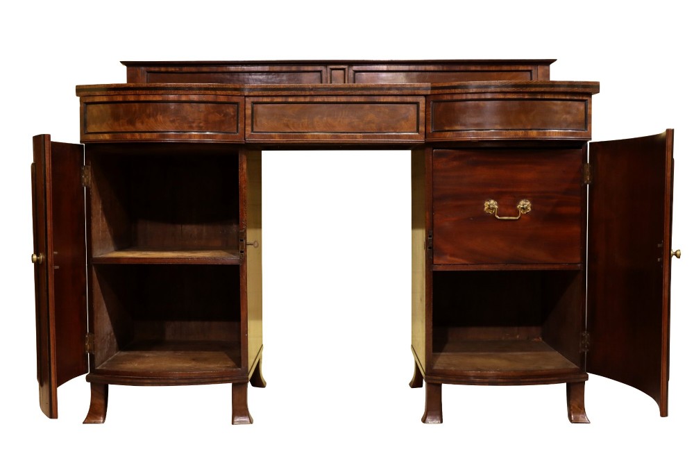An early 19th-century Regency flame mahogany bow-front pedestal sideboard with twin cupboard doors, a central drawer, and a low rear gallery. View V