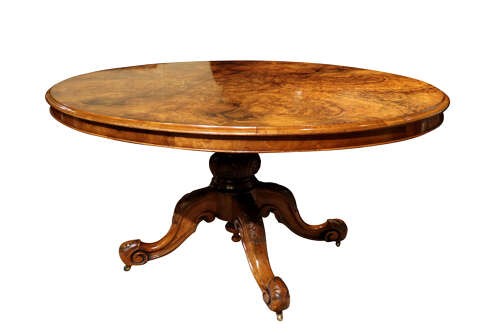 A Victorian oval burr walnut breakfast table featuring rich timber grain and a carved quadrapod base with scroll feet. View IV
