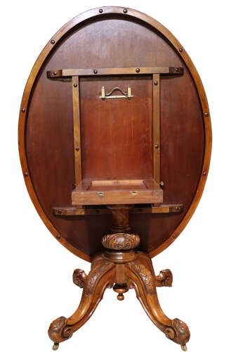 A Victorian oval burr walnut breakfast table featuring rich timber grain and a carved quadrapod base with scroll feet. View VI