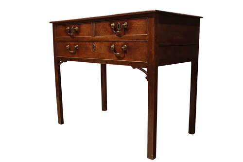 A George III dark oak lowboy featuring a rectangular top over three drawers with brass swan-neck handles, supported on straight square legs. View IV