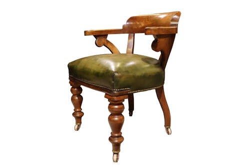 A Victorian golden oak library chair featuring a curved backrest, turned front legs with castors, and an olive green leather seat trimmed with brass studs. View IV