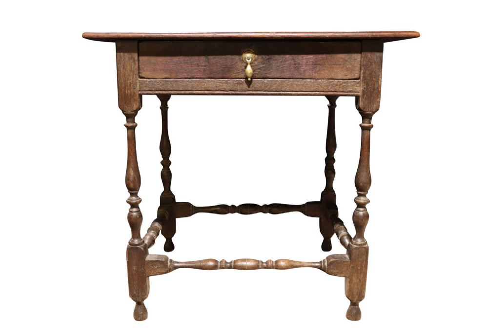 An 18th-century George II solid oak side table featuring a single drawer with a brass teardrop pull, turned legs, and stretchers.