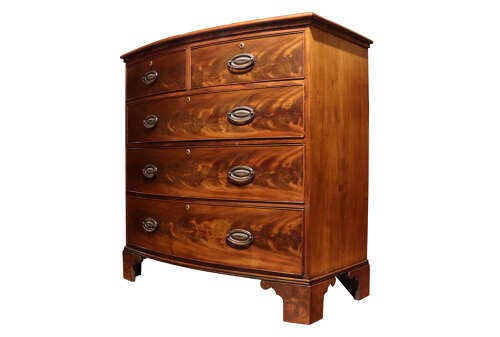 A Regency period bow-front mahogany chest of drawers featuring two short drawers over three long drawers with oval brass handles and bracket feet. View IV