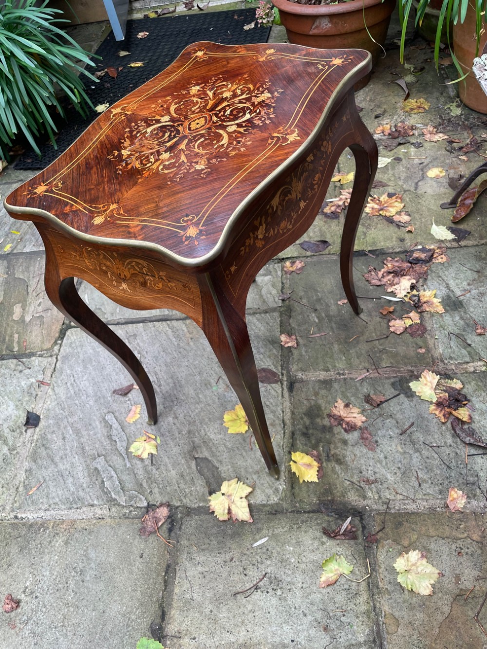 A late 19th-century French marquetry sewing table featuring floral wood inlay on a serpentine top, brass edging, and slender cabriole legs. View II